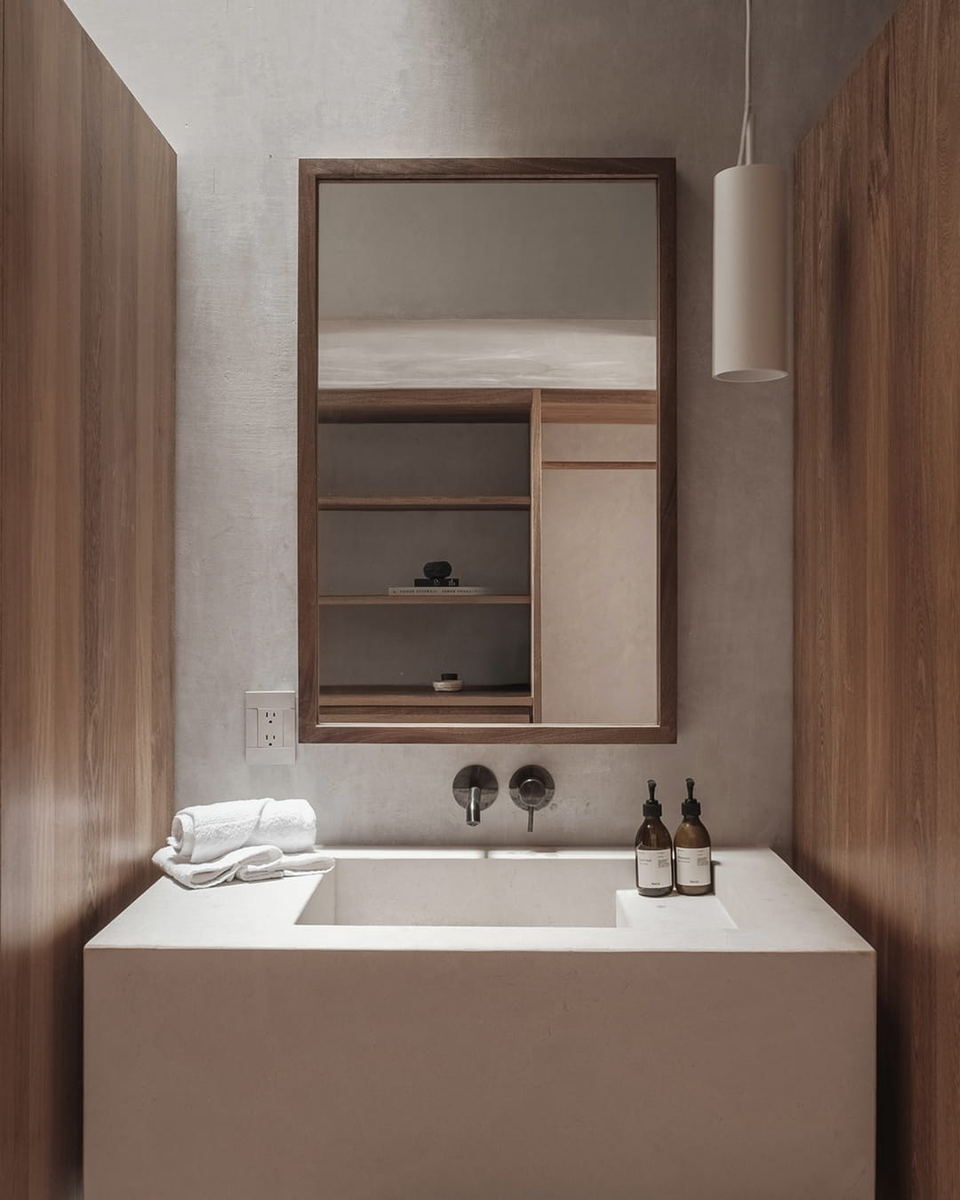 Hotel Notto: Lavabo de baño con espejo enmarcado en madera y almacenamiento integrado.